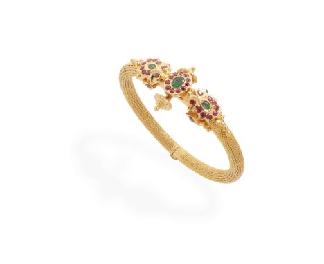  An emerald and ruby bangle  Of hinged design, the central motif set with oval-cut emeralds and round-cut rubies, stamped 22k