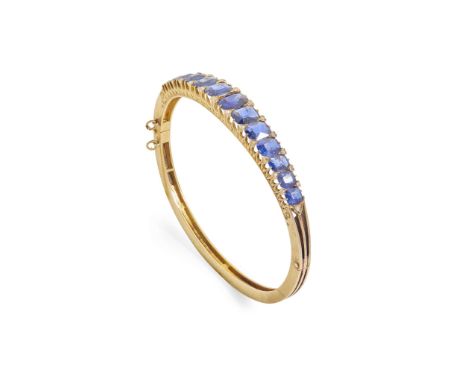  A sapphire and diamond bangle  Of hinged design, claw-set with a row of graduated cushion-cut sapphires, diamond chip detail