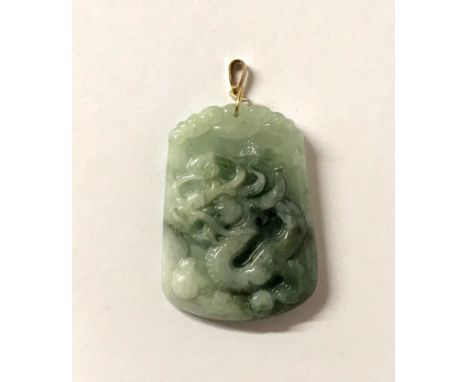 A carved Chinese jade dragon pendant on a 9ct gold fitting. H.4.5cms