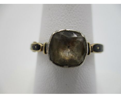 A yellow gold coloured George III mourning ring set with a cushion shaped stone, possibly a white sapphire, black enamel oute