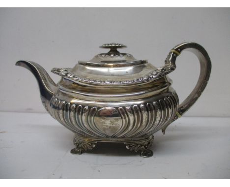 A George III silver teapot, makers mark rubbed, London 1817, of demi reeded and fluted form, floral and foliage decoration to