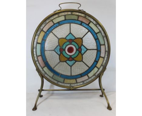 Late 19th/early 20th century firescreen, the circular leaded stained glass panel with flowerhead motif in brass frame with si