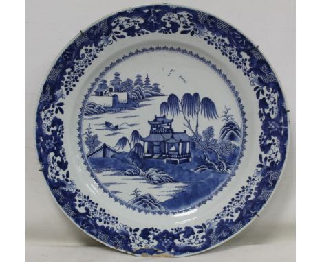 Large 18th century Chinese blue and white porcelain charger of circular form, the central panel depicting pavilions by a lake