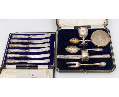 A George V silver matched Christening set comprising: egg cup and egg spoon with gilt bowls, a fork, knife, spoon and napkin 