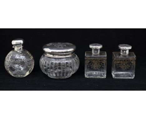 A collection of four early 20th Century silver mounted toilet bottles to include: 1. A pair of Edwardian cologne / scent bott