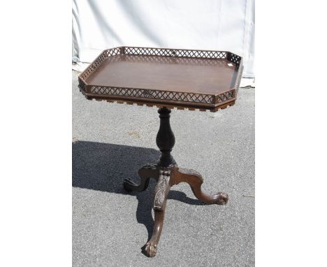 A George III style mahogany canted rectangular tilt top tripod table, lattice pierced gallery, foliate carved baluster column