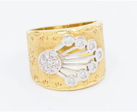 An 18ct gold and diamond set dress ring comprising a textured wide gold band with a central fan like white gold decorated ter