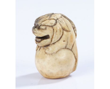 Japanese Edo period stag horn netsuke, as a dog of foo on a ball, 4.5cm high