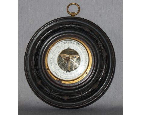 Messinstrument. Historisches rundes Barometer mit Glasabdeckung montiert in dunkelbrauner runder, verzierter Holzeinfassung. 