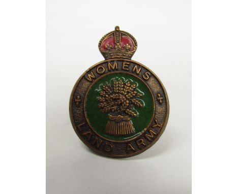 A WWII Woman's Land Army badge produced with crown surmounting green and gold coloured emblem of wheat sheaf