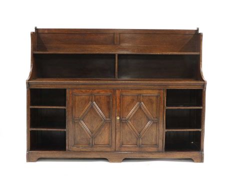 An Arts and Crafts oak bookcase, c.1890, by Shoolbred &amp; Co., with a raised back with a sectional shelf, over a central la