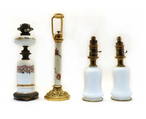 Four Victorian and Edwardian oil lamps, comprising: a pair of white pottery by Bright (late Argand &amp; Co), 43cm high, with