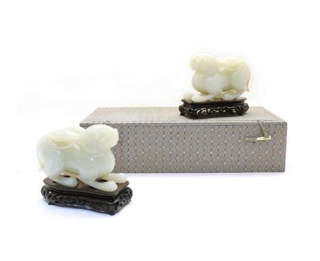 A pair of Chinese jade carvings, 20th century, of two recumbent rabbits, the stone of greyish-white tone, wood stands (4)Cond