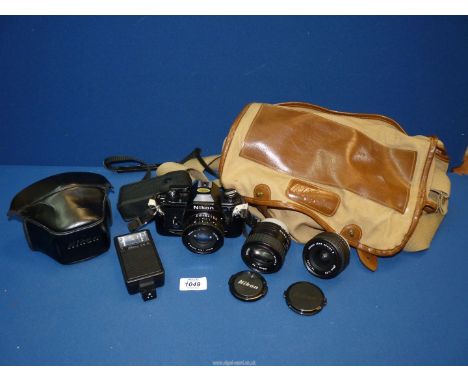 A Nikon 35mm camera, in a brown canvas camera bag with three lenses and a flash gun.