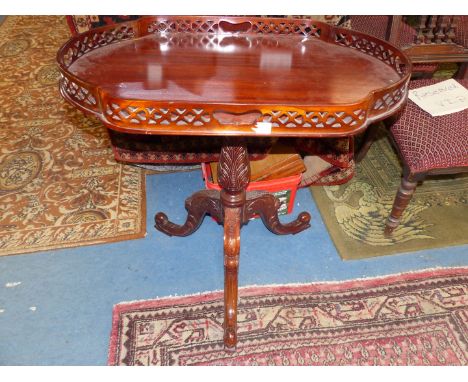 A Mahogany occasional Table, the shaped top having a fretworked frieze and standing on a turned and carved pillar on three sp