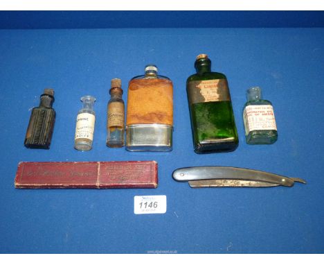 A glass hip flask with leather cover and various pharmaceutical bottles along with a boxed straight razor.