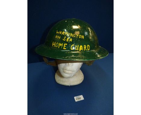 A 'Home Front' tin Helmet painted green with Warmington-on-Sea Home Guard written in yellow.
