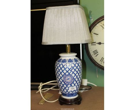 An oriental style blue and white Table Lamp with wooden base and cream shade, 21" tall.