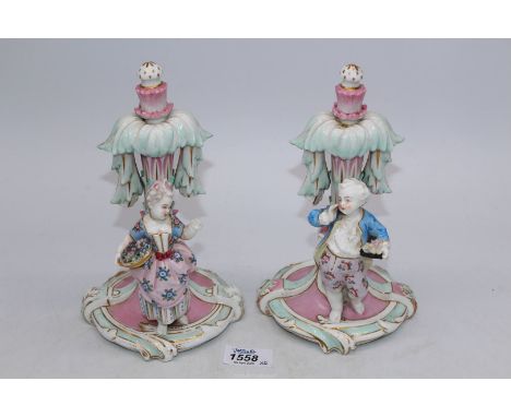 A pair of Meissen marked [ only one ] figures of a young girl and boy in front of a pillar decorated with Acanthus leaves in 