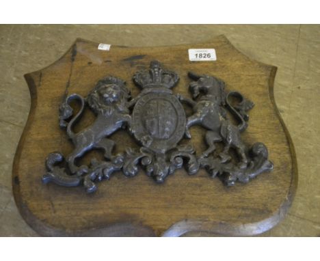 Cast metal Royal coat of arms, mounted on a wooden shield together with a wooden bow saw