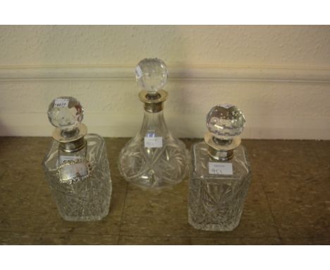 Three various silver mounted cut glass decanters with stoppers, together with one silver decanter label