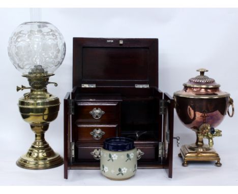 A MAHOGANY SMOKERS CABINET with a lifting top, twin oval glazed doors, three short drawers and a stoneware tobacco jar, 33cm 