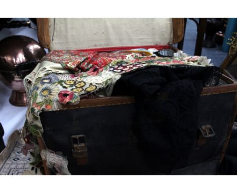 AN OLD LEATHER BOUND TRUNK  containing a quantity of materials, lace and trimmings to include a printed cashmere shawl, black