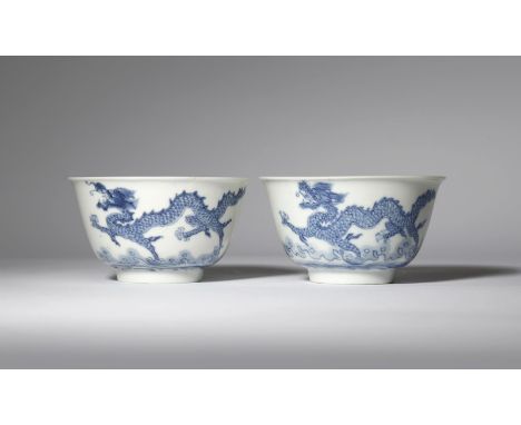 A PAIR OF CHINESE BLUE AND WHITE 'DRAGON' BOWLS KANGXI 1662-1722 Each painted with two scaly dragons in flight above crashing
