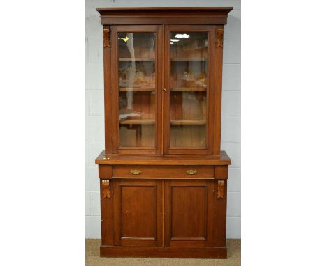 A late Victorian mahogany bookcase, the projecting cornice above foliate appliques and pair of glazed cupboard doors enclosin