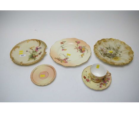 A Royal Worcester circular plate, decorated with flowerheads in shades of yellow, cream and pink, within a scrolling gilt bor