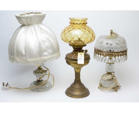 An early 20th C brass oil lamp, with amber glass shade, 47cms high overall; together with a crystal and gilt metal table lamp