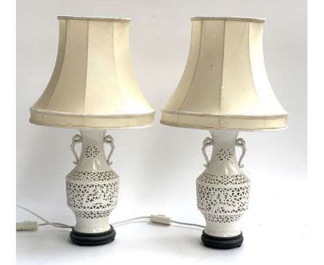A pair of white ceramic table lamps with shades on carved wood bases, height to top of shades 64cm 