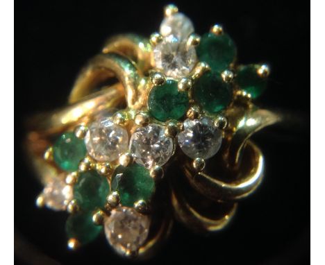 An emerald and diamond free form cluster ring, eight round brilliant cut diamonds and eight round cut emeralds, set to a mult