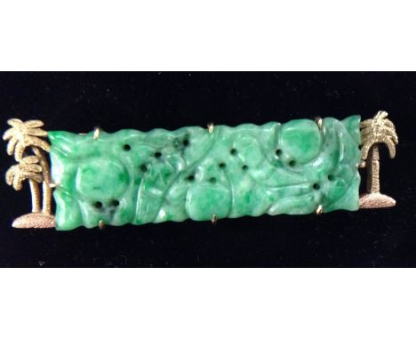 A carved jade panel brooch, rectangular jade table, carved with flowers and roundels, within Palm Tree cast yellow metal fram