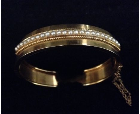 An Edwardian 14ct gold and seed pearl hinged bangle, cased, 23g