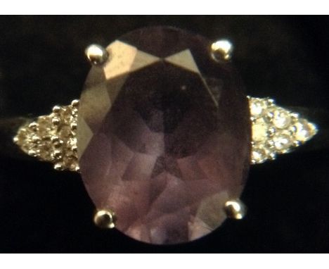 A tanzanite and diamond ring, central oval violet/grey tanzanite, flanked by two triangular clusters of six round brilliant c