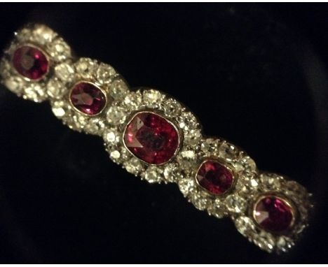 A Garrard's diamond and ruby five panel brooch, central oval ruby, surrounded by a ring of twelve round old brilliant cut dia