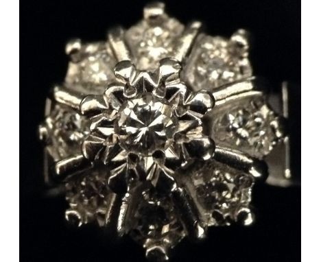 A nine stone diamond flower head cluster ring, central raised diamond, surrounded by a band of eight individual diamond secti