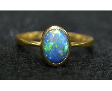 A black opal solitaire ring, oval black opal flashing, blue, green, purple yellow and orange colour play, approx 11mm x9mm x 