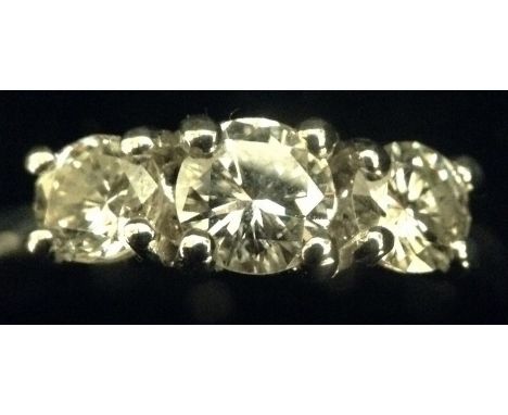 A diamond three stone ring, central round brilliant cut diamond, flanked to each side by a conforming smaller diamond, total 