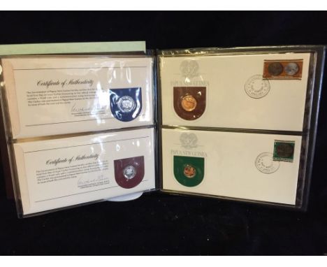 A presentation folder of 1st Day covers containing First Day Covers with commemorative coins and stamps celebrating Papua New
