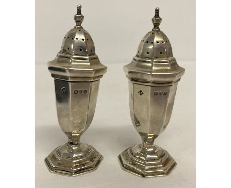 A boxed pair of Edwardian silver pepperettes, hallmarked Chester 1907.  Octagonal shaped bodies raised on a stepped and weigh