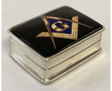 A small white metal pill box marked "Sterling" with ceramic plaque to lid showing Masonic symbol.   Approx. 1.5 x 3 x 2.5cm.