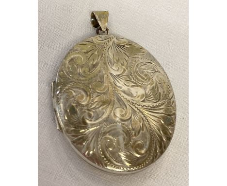 A large vintage silver locket with floral engraved decoration to front.  Hallmarked Birmingham 1977. Approx. 6.5 cm tall incl