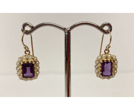 A pair of 9ct gold amethyst and seed pearl earrings in a drop style.  Emerald cut amethysts surround by 14 small seed pearls.