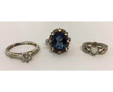 3 stone set silver and white metal dress rings.  A cocktail ring with large central blue stone surrounded by  small clear sto