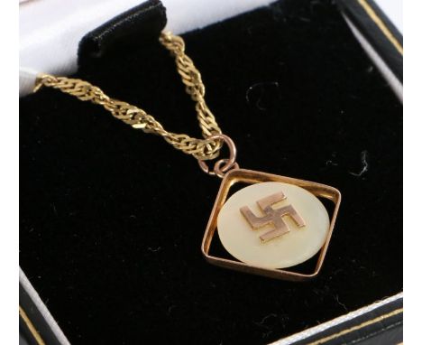 A 9 carat yellow gold pendant with a Swastika set on mother of pearl suspended from a 9 carat yellow gold twisted chain.Penda