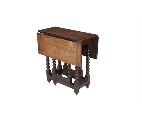 A LATE 17TH CENTURY OAK DROP-LEAF TABLE, the rectangular top on bobbin turned gate leg supports, joined by solid stretchers a