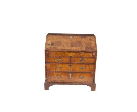 AN EARLY GEORGIAN WALNUT SLOPE-FRONT BUREAU, c.1720, with feathered inlay top and cross-banded slope opening to reveal an arr