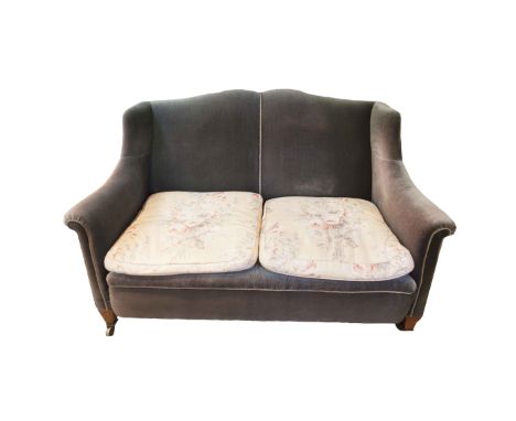 A HOWARD STYLE UPHOLSTERED TWO SEAT SOFA, with raised back and outscrolling sides on short tapering legs and brass castors. 1